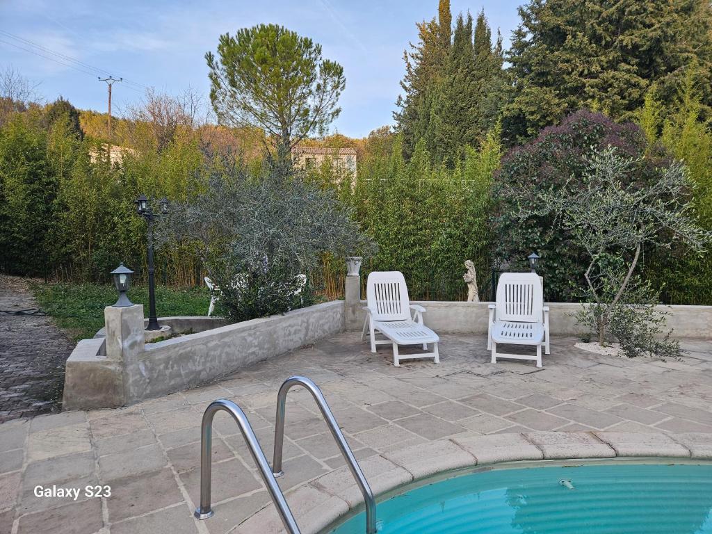 two white chairs sitting next to a swimming pool at Guest house calme avec accès jardin et piscine in Flayosc