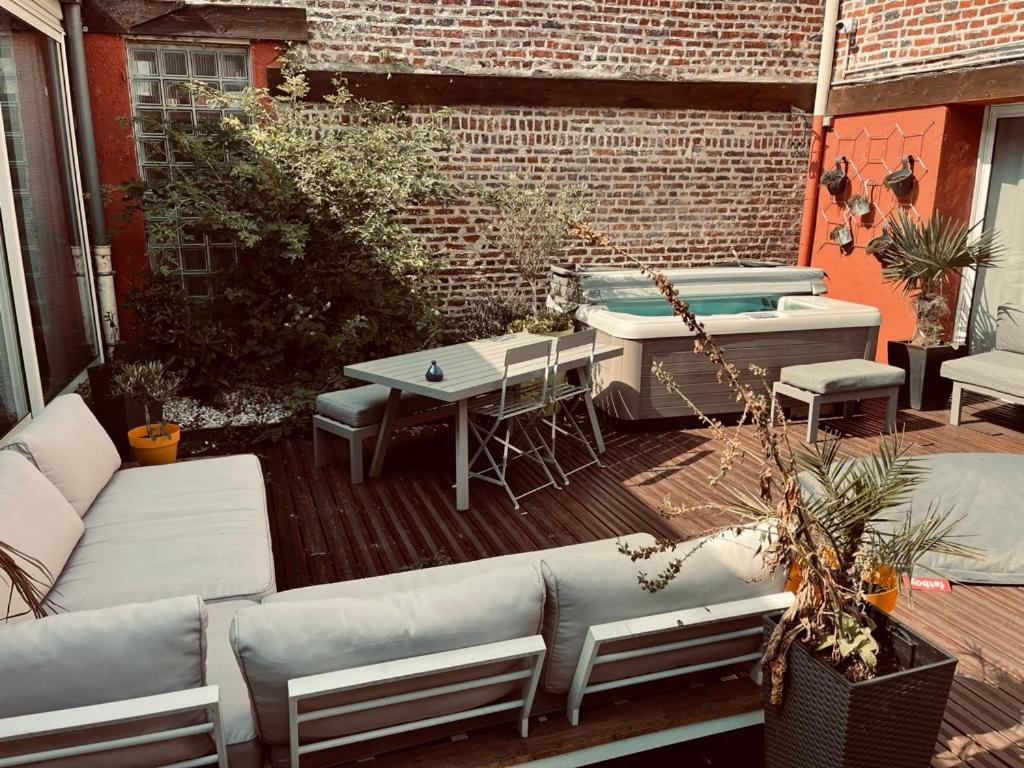 a patio with a couch and a table and a hot tub at Studio indépendant et calme avec Jacuzzi à Lille in Lille