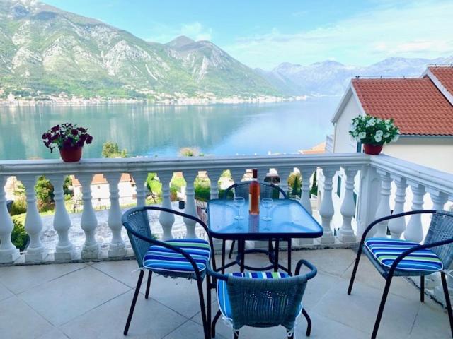 einen Tisch und Stühle auf einem Balkon mit Blick auf das Wasser in der Unterkunft An artist's dream in Dobrota