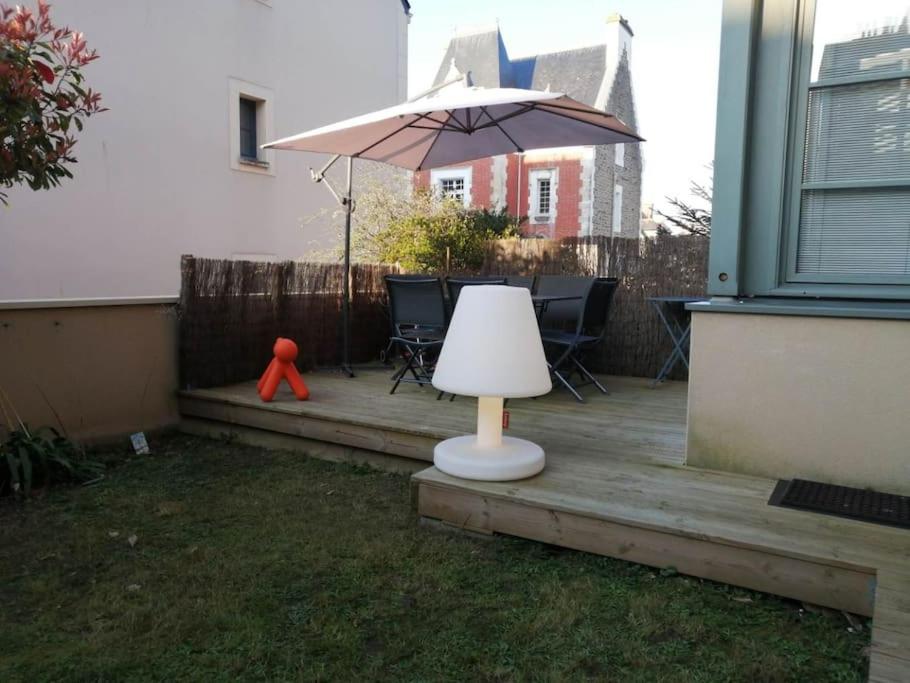 eine Veranda mit einem Sonnenschirm, einem Tisch und Stühlen in der Unterkunft Cocon familial avec jardin au cœur de St Servan in Saint-Malo