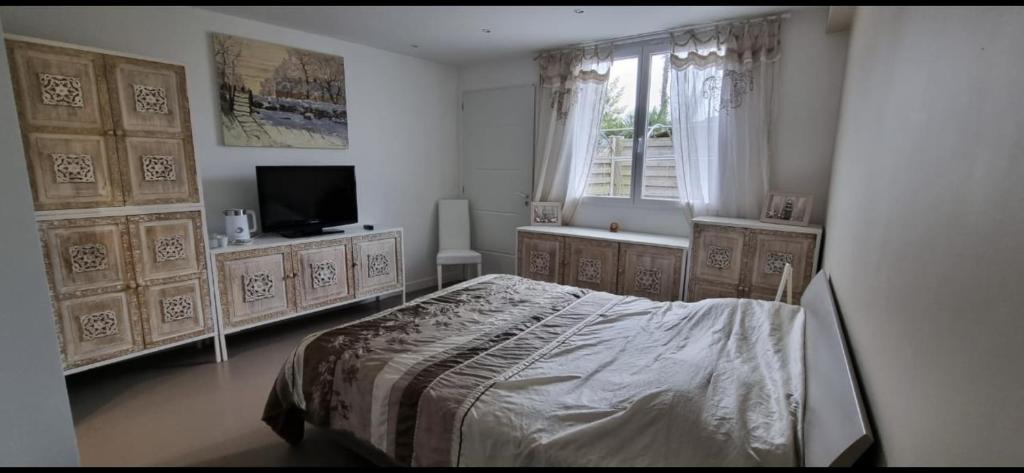 a bedroom with a bed and a television and a window at Belle chambre privée avec douche et toilette indépendantes dans une magnifique villa in Andernos-les-Bains