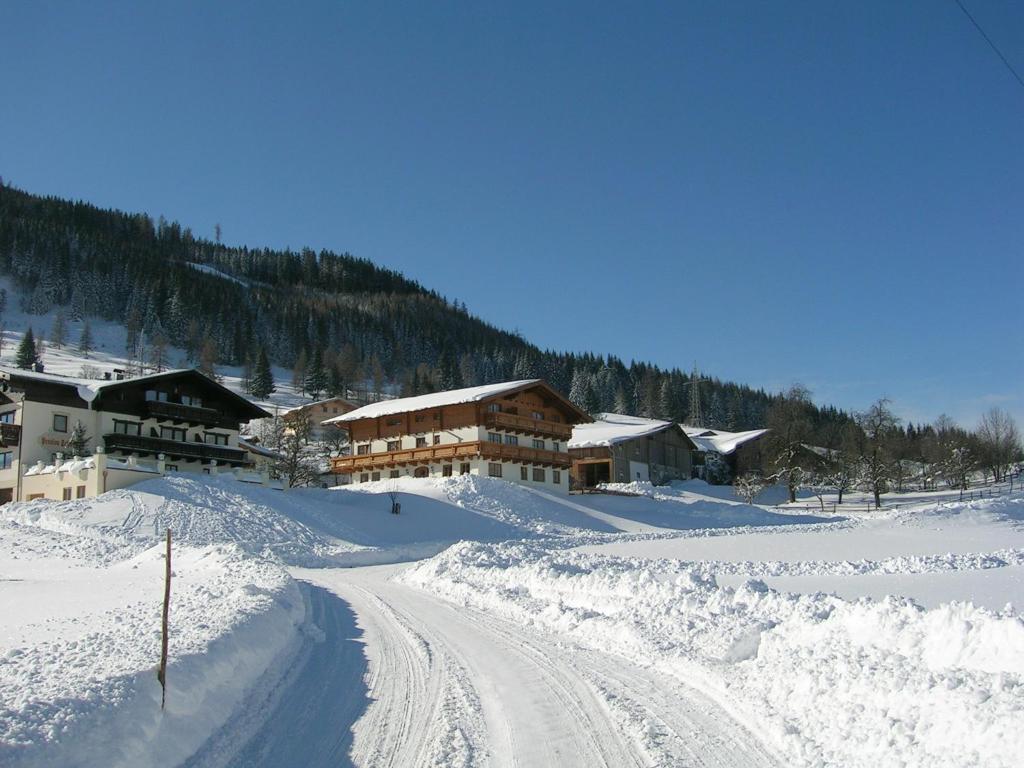 a snow covered road in front of a ski lodge at Sauschneid Hof in Taxenbach