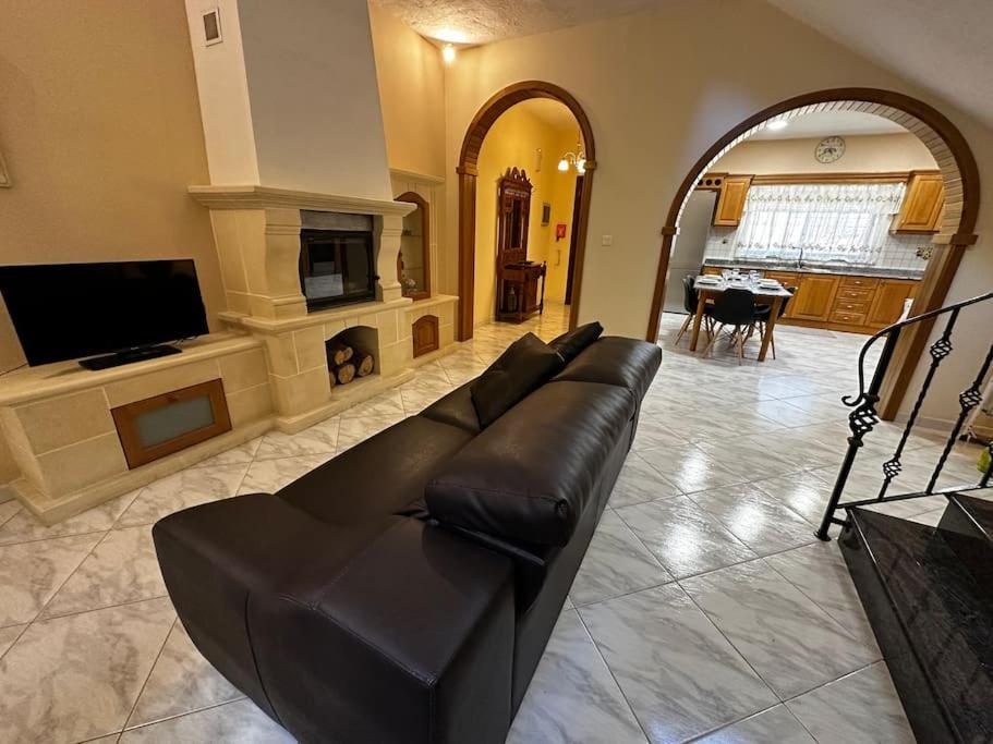 a living room with a black leather couch and a fireplace at Casa Del Mare, 3Bedroom House in Marsaxlokk Fishing Village in Marsaxlokk