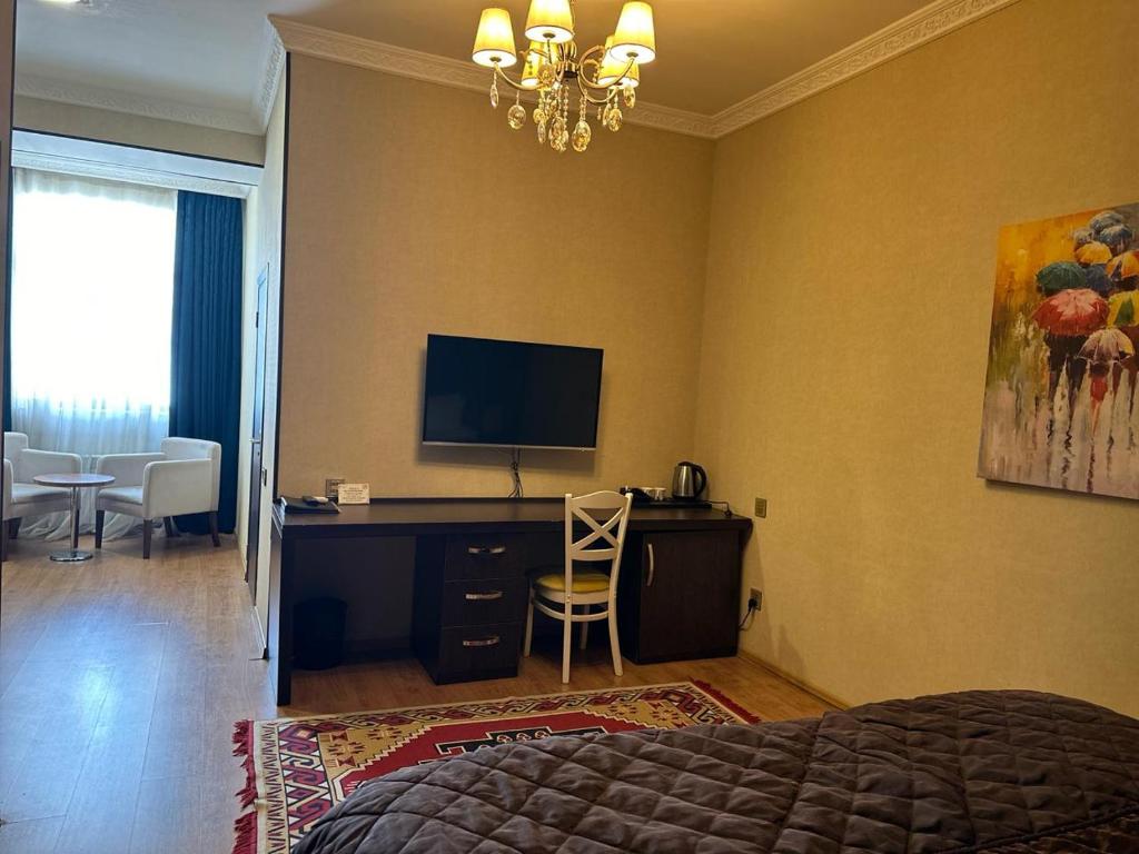 a bedroom with a bed and a desk with a television at Sherlock Hotel Baku in Baku
