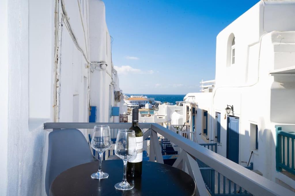a table with two glasses and a bottle of wine on a balcony at My White Studio Mykono Town in Mikonos