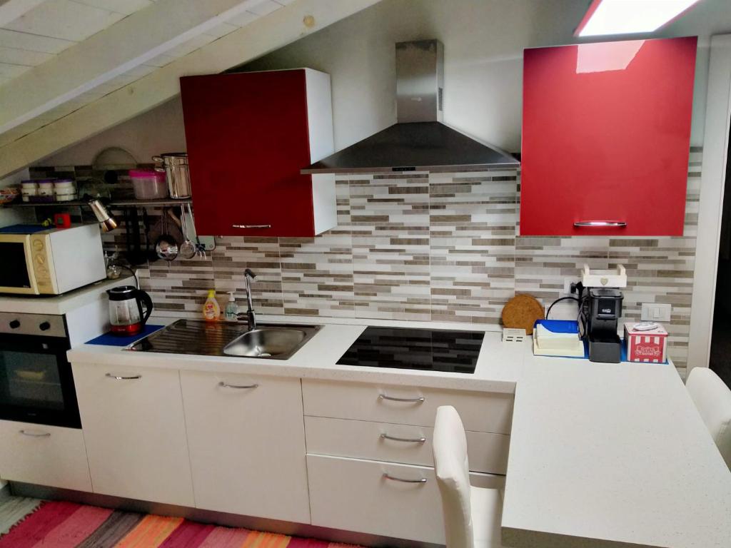 uma cozinha com balcões brancos e armários vermelhos em Appartamenti Centro Seriate em Seriate