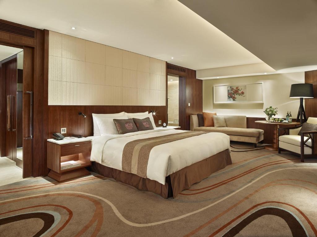 a bedroom with a large bed and a living room at White Swan Hotel in Guangzhou