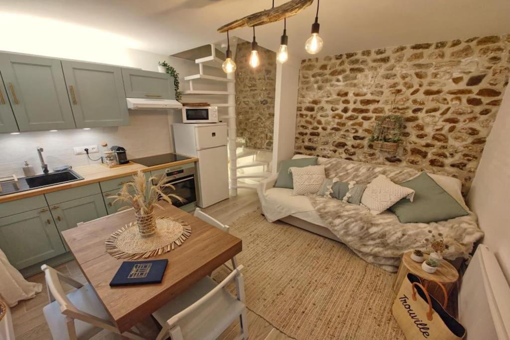 eine Küche und ein Wohnzimmer mit einem Sofa und einem Tisch in der Unterkunft Le cocon du pêcheur in Trouville-sur-Mer