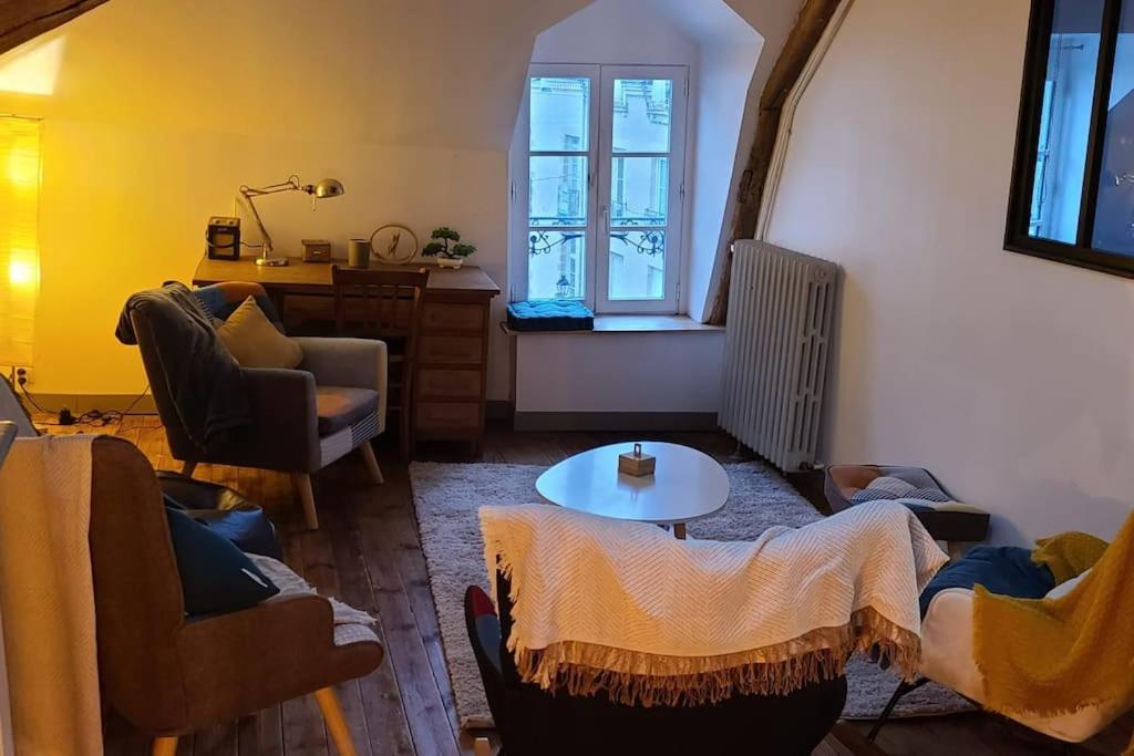 sala de estar con sillas, mesa y ventana en Appartement Intra murailles, en Vannes