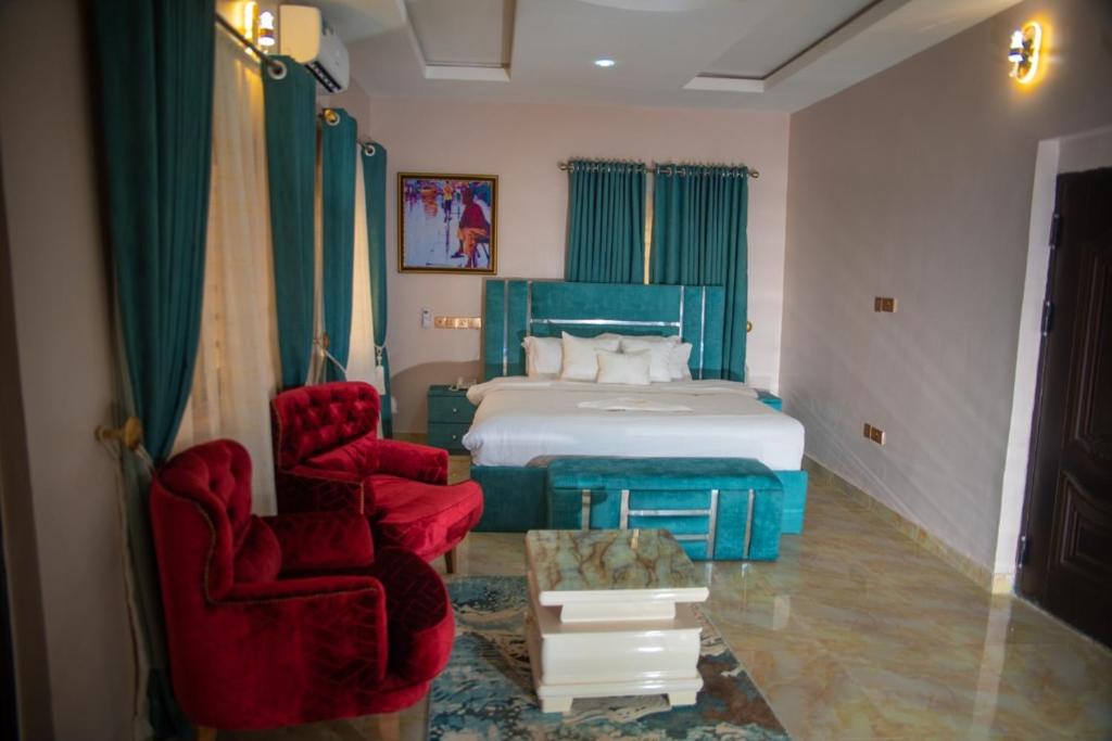 a bedroom with a bed and two red chairs at Ennys Court in Akure