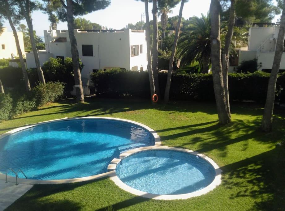 a large blue swimming pool in a yard with trees at Apartamento La Caleta in Les tres Cales