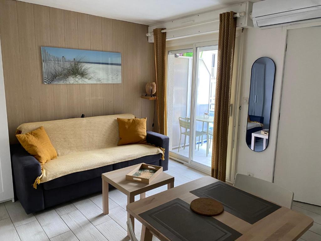 ein Wohnzimmer mit einem Sofa und einem Tisch in der Unterkunft Studio à 20m de la plage in Palavas-les-Flots