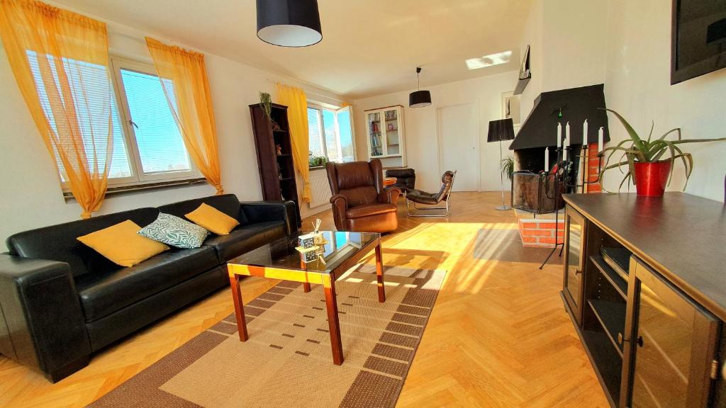 Smålands gemütliche Apartments direkt am Fluss في Högsby: غرفة معيشة مع أريكة سوداء وطاولة