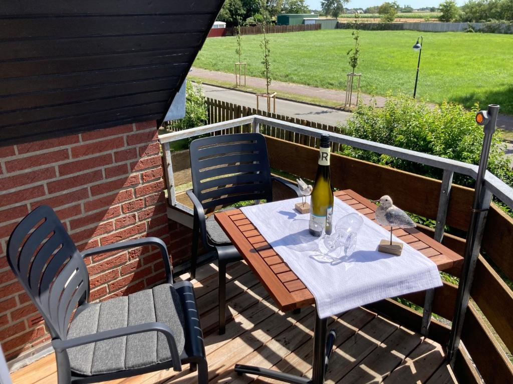 einen Tisch mit einer Flasche Wein und zwei Stühlen in der Unterkunft Vinnenhus Wohnung 06 in Cuxhaven