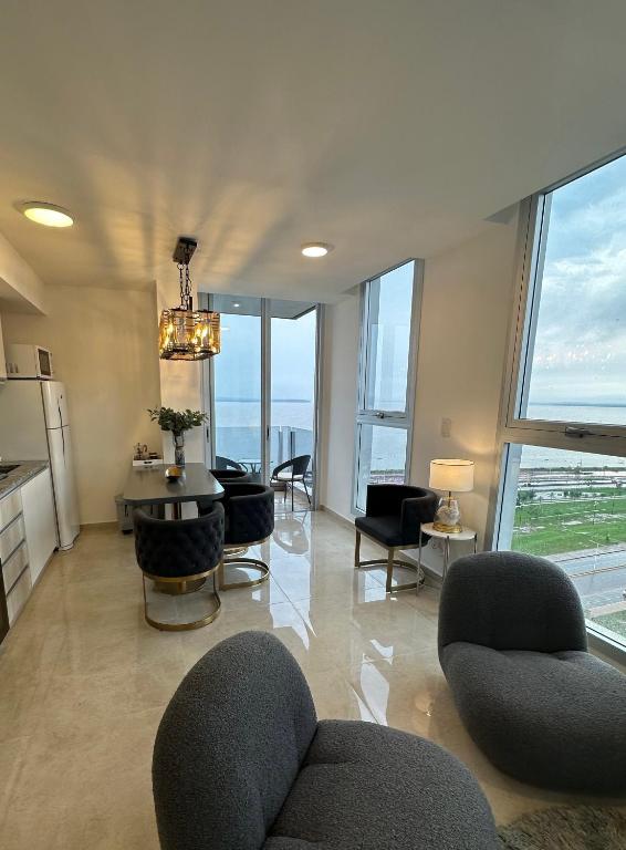a living room with a table and chairs and windows at Departamento chic Costanera Posadas in Posadas
