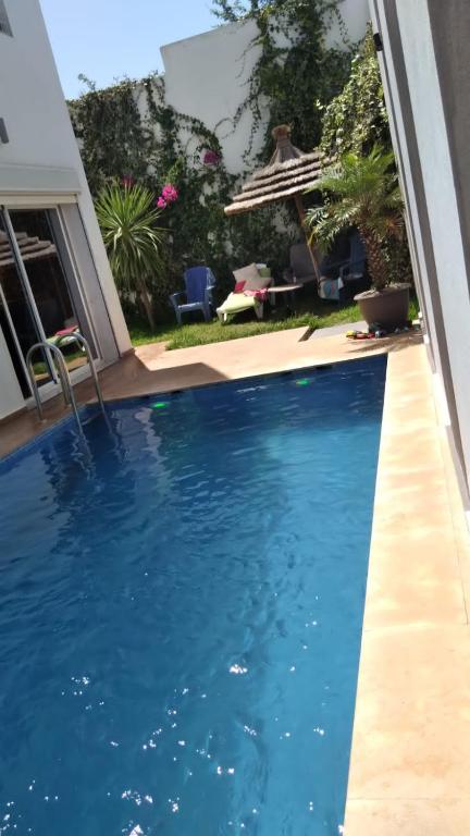 een zwembad met blauw water in een achtertuin bij Villa avec piscine in Plage de Mehdia