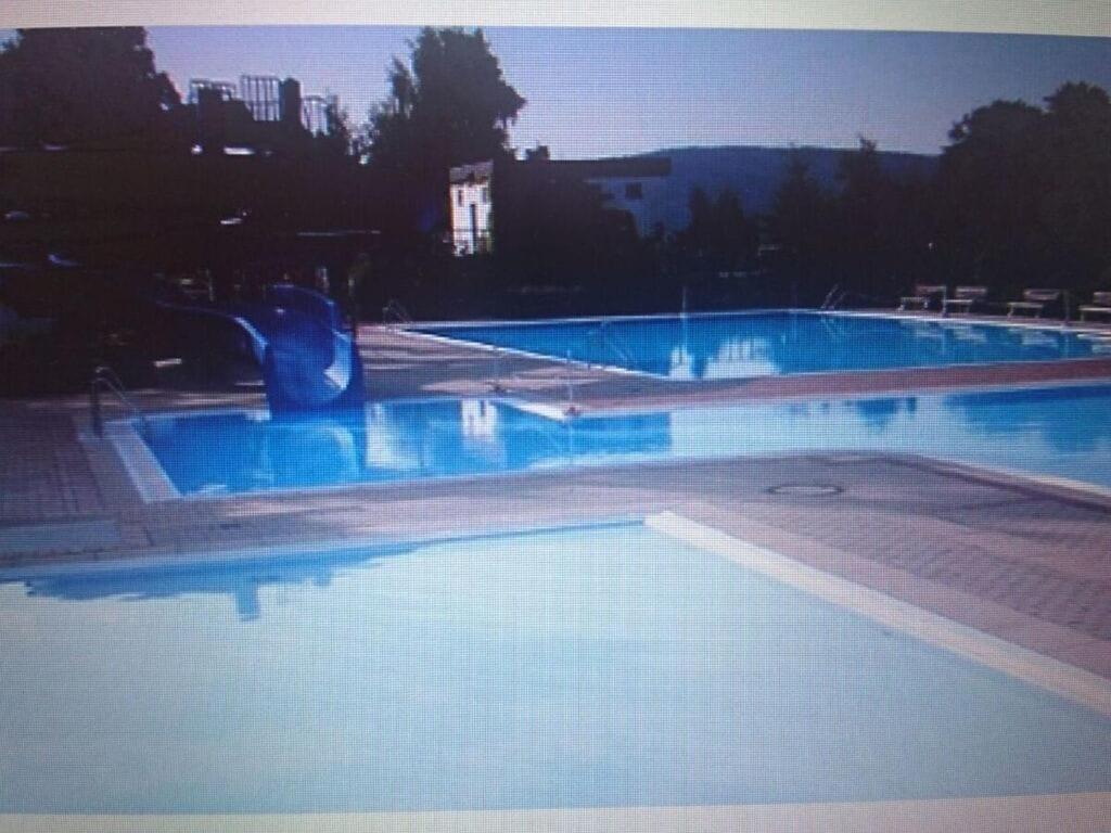 a large swimming pool with blue water at Holiday home Am Dachsberg in Burkhardtsdorf