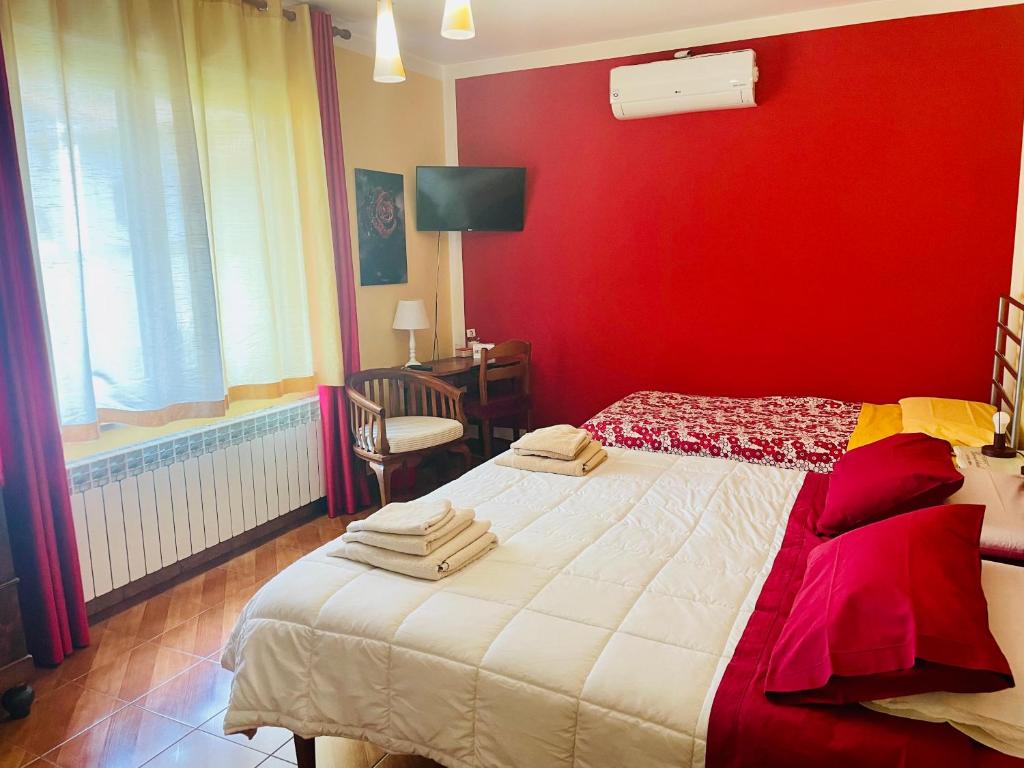 a bedroom with a red wall and a bed at Bed and Breakfast L'Albero Maestro in Borgofranco dʼIvrea