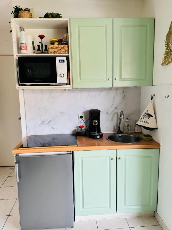 a kitchen with green cabinets and a sink and a microwave at Appartement bohème chez Kawa in Cavalaire-sur-Mer