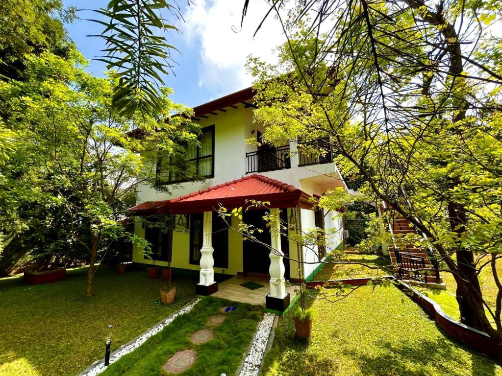 ein Haus inmitten eines Gartens mit Bäumen in der Unterkunft Sigiriya Cashew Palace Resort in Daganapothaha