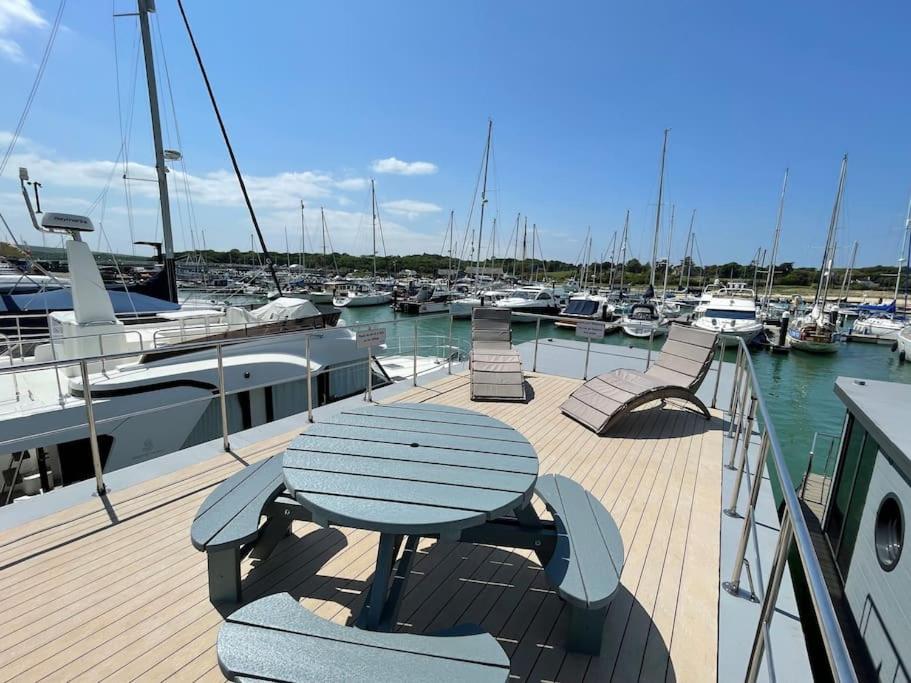 a wooden deck with a table and chairs on a boat at Yarmouth Waterlodge Floating Apartments 2 in Yarmouth