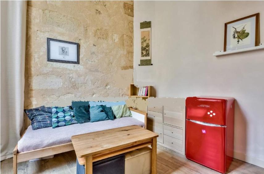 Cette chambre comprend une table et un réfrigérateur rouge. dans l'établissement Coquet studio Bordeaux proche tram et Quais, à Bordeaux