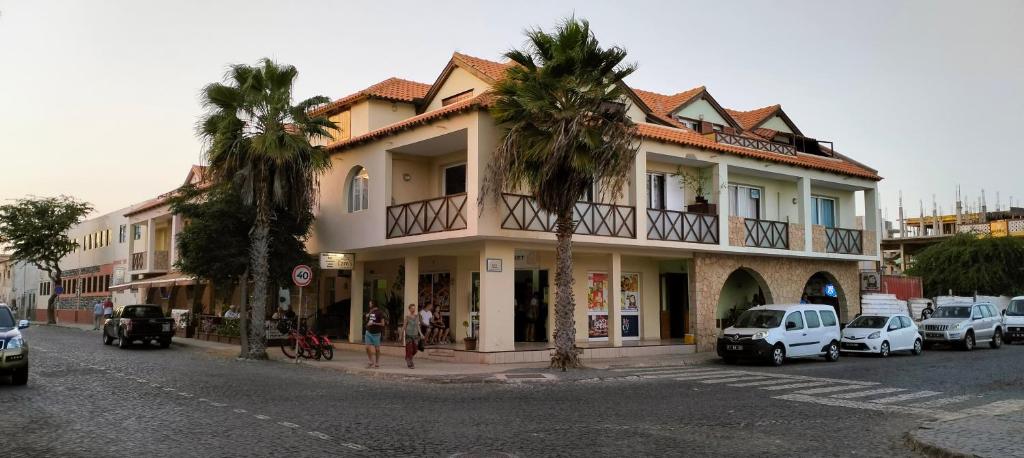 a building with palm trees on the side of a street at Residencial Ilha do Maio App 101 in Santa Maria