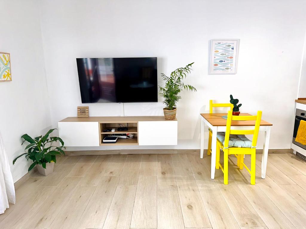 uma sala de estar com uma televisão e uma mesa e cadeiras em Hope house Lanzarote em Puerto del Carmen