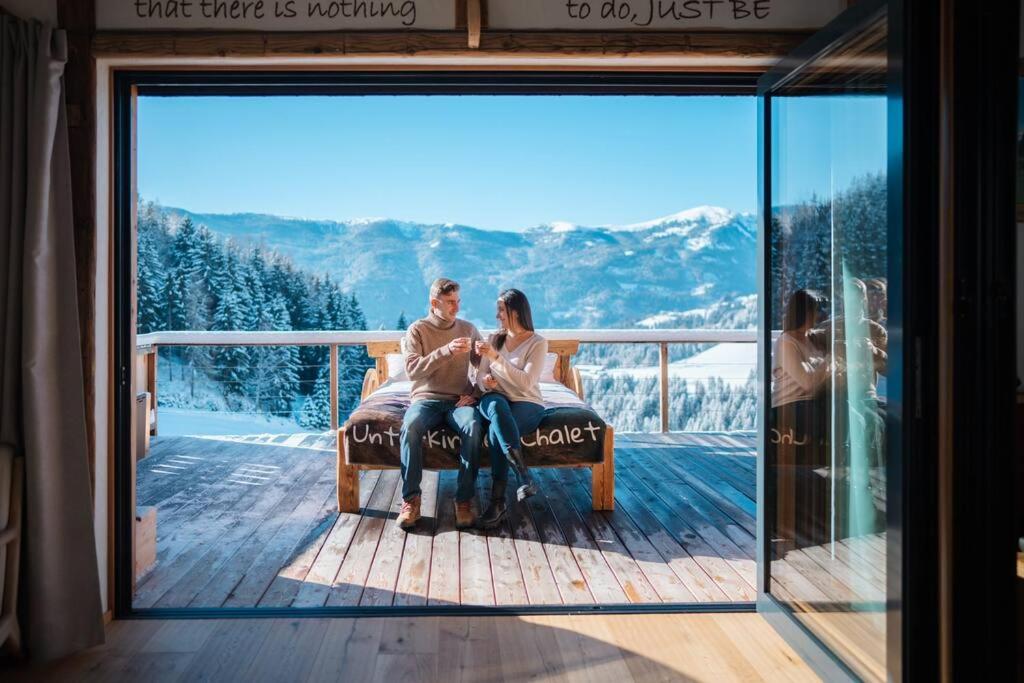 a man and woman sitting on a bench on a deck at Unterkircher Chalet in Arriach