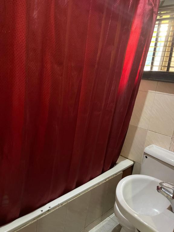 a bathroom with a red shower curtain and a toilet at OD-V!CK'S BUDGET ROOMS, 24HR POWER, SECURITY, DSTV in Abuja
