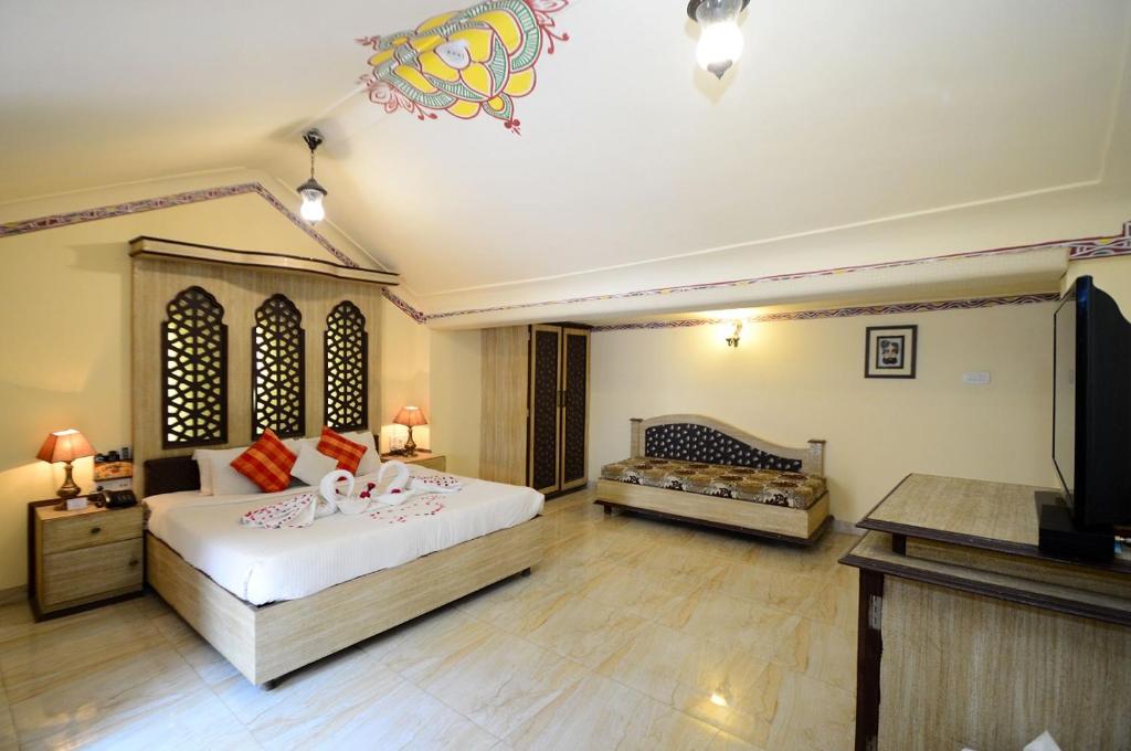 インドールにあるCHOKHI DHANI INDOREのベッドとテレビが備わる広い客室です。