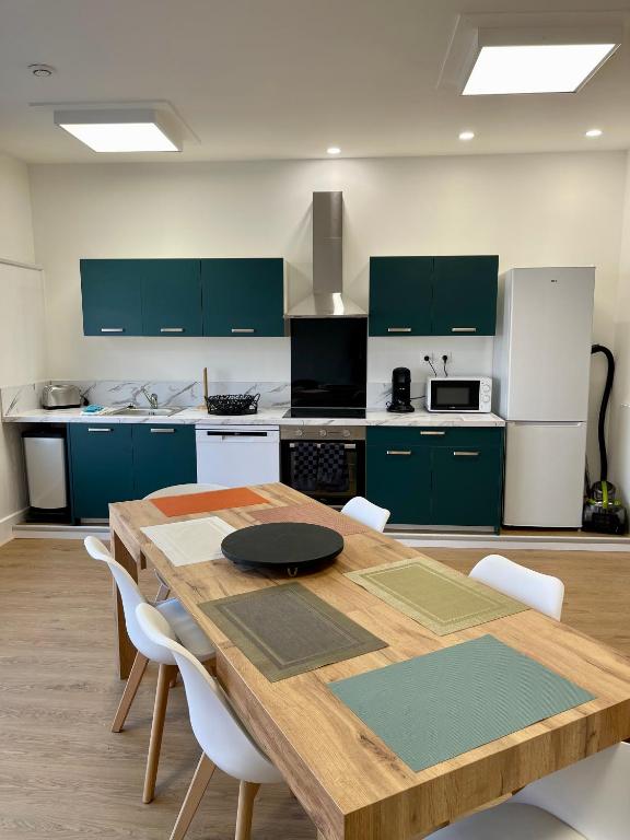 une cuisine avec une table en bois et une cuisine avec des armoires vertes dans l'établissement Maison Spacieuse 12pers et 4 SdB - Tout Confort - Parking Gratuit, à Anzin