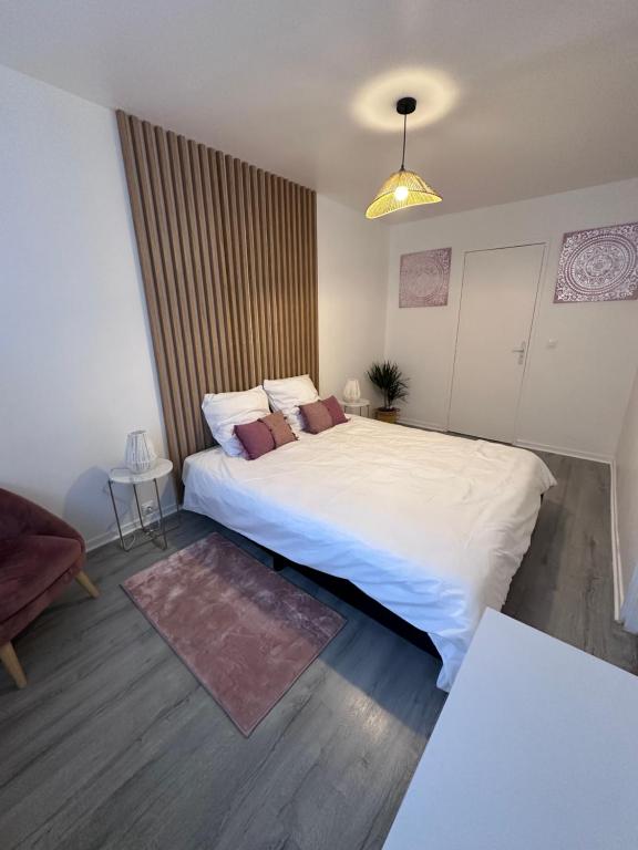 - une chambre avec un grand lit blanc et une chaise dans l'établissement Le Cosy - Centre Ville - 2 pièces, à Beauvais