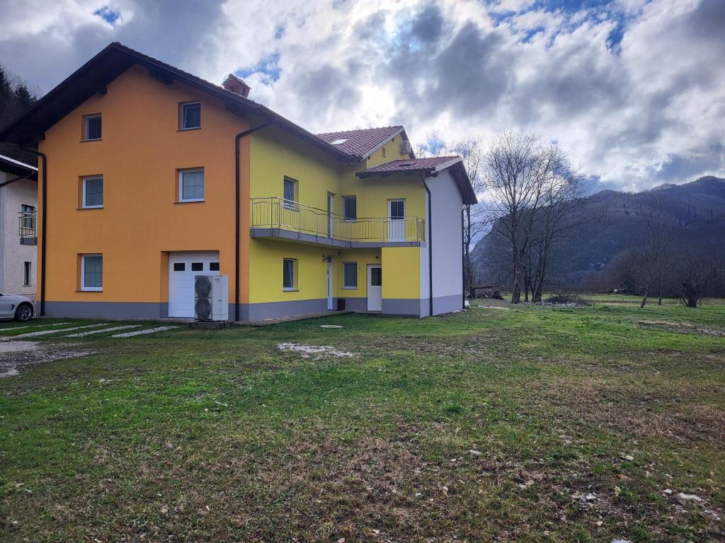 a yellow and white house with a grass yard at apartma jermol in Most na Soči