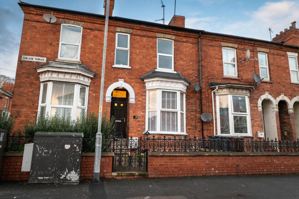 a red brick house with a black gate at Heart of the City beautiful 3 bed 2 bath sleep 6 in Lincoln