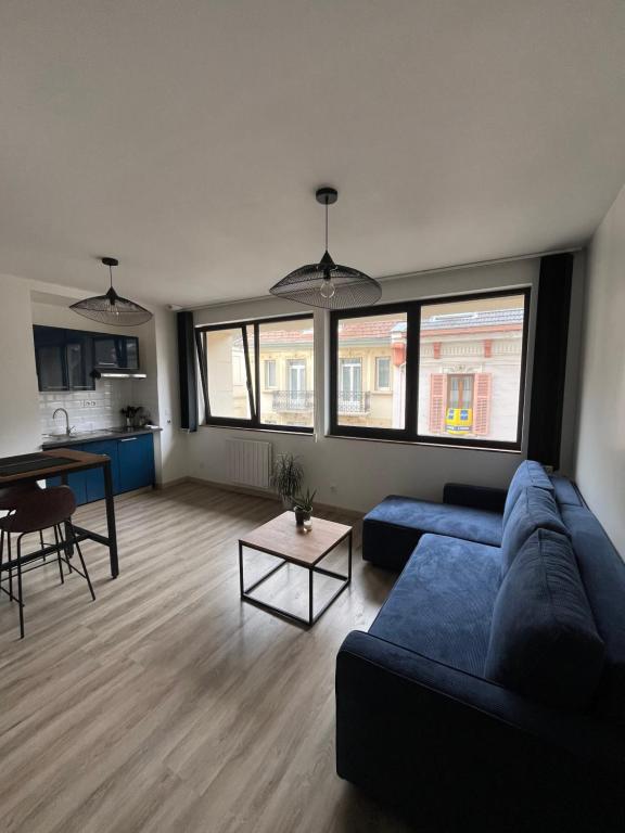 un salon avec un canapé bleu et une table dans l'établissement Appart plein centre - Astoria, à Aix-les-Bains