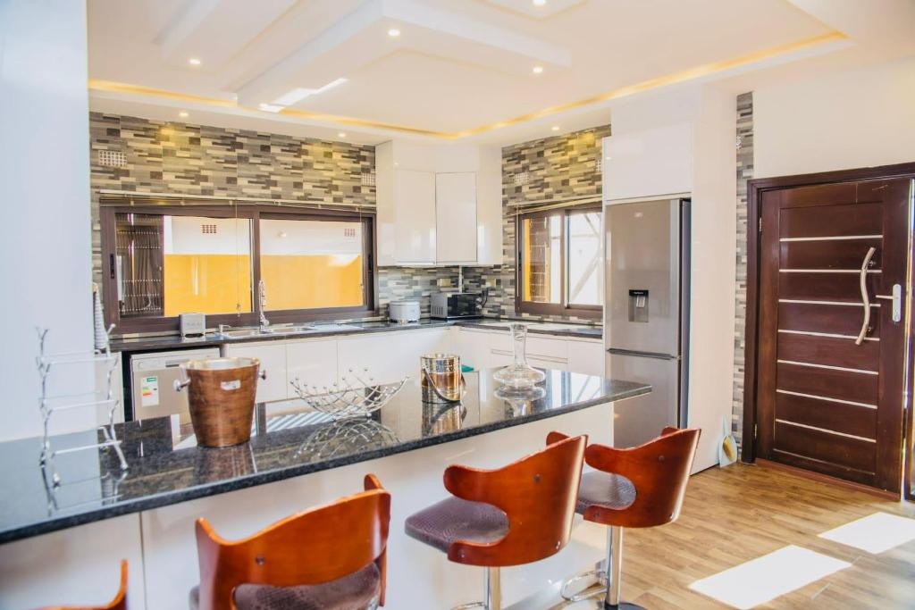 a kitchen with a counter and some orange chairs at Z Apartment (4bedroom) in Lusaka