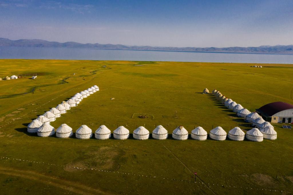 an aerial view of a field with a row of white tents at AK-SAI TRAVEL yurt camp at Son Kul lake in Song-Kul