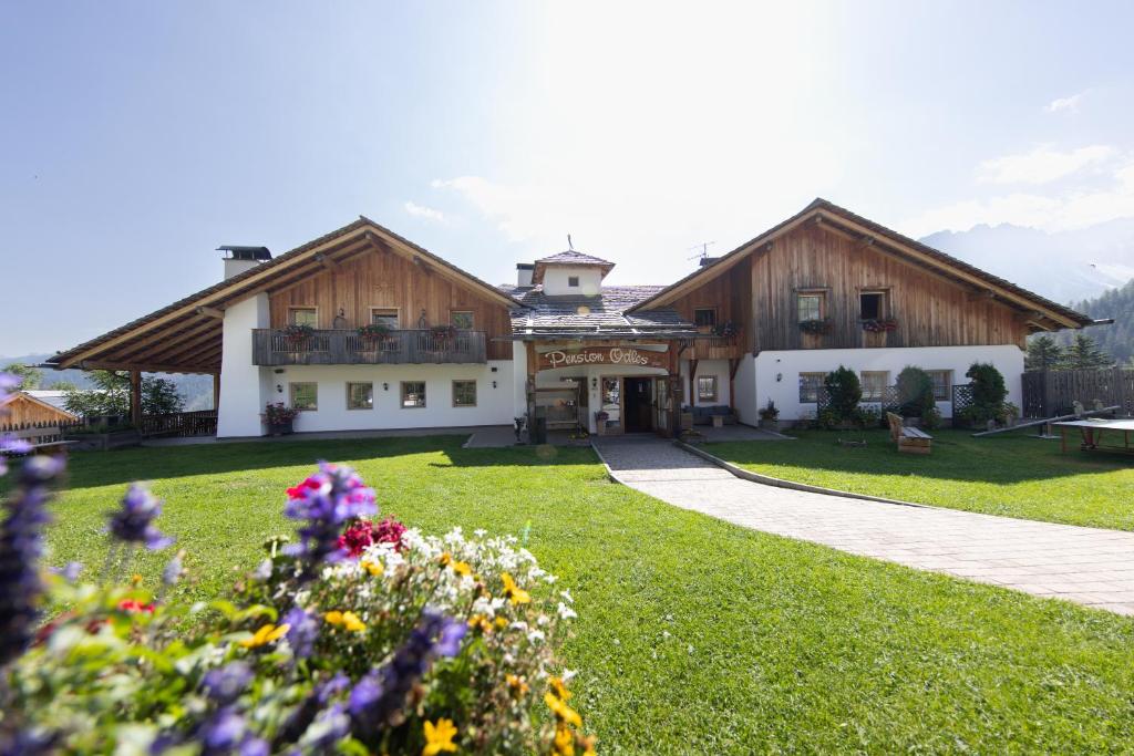 a large building with flowers in front of it at Hotel Pension Odles in San Martino in Badia