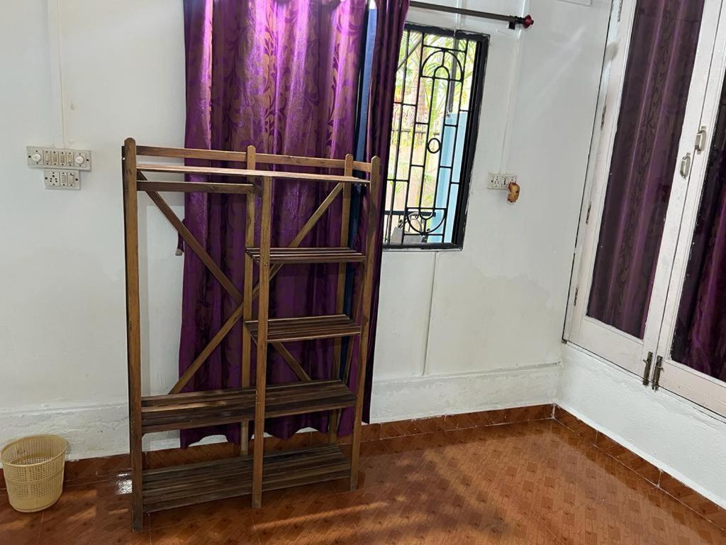 ein Holzregal in einem Zimmer mit lila Vorhängen in der Unterkunft Oceanic guest house in Canacona