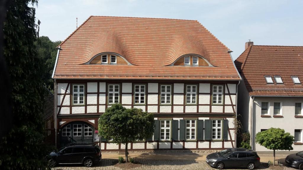 a house with a red roof and two cars parked in front at Ferienwohnung "Im Pfarrhaus Marlow" in Marlow