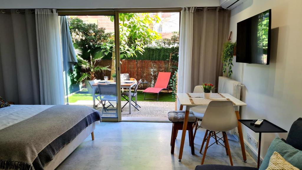 1 dormitorio con 1 cama, mesa y sillas en Studio Sun-Beach avec parking et jardin - 500m des plages de Juan Les Pins en Antibes