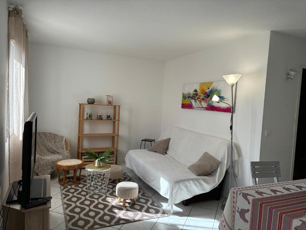 a living room with a white couch and a television at Les clés de Jonzac-conciergerie Nid de Douceur in Ozillac