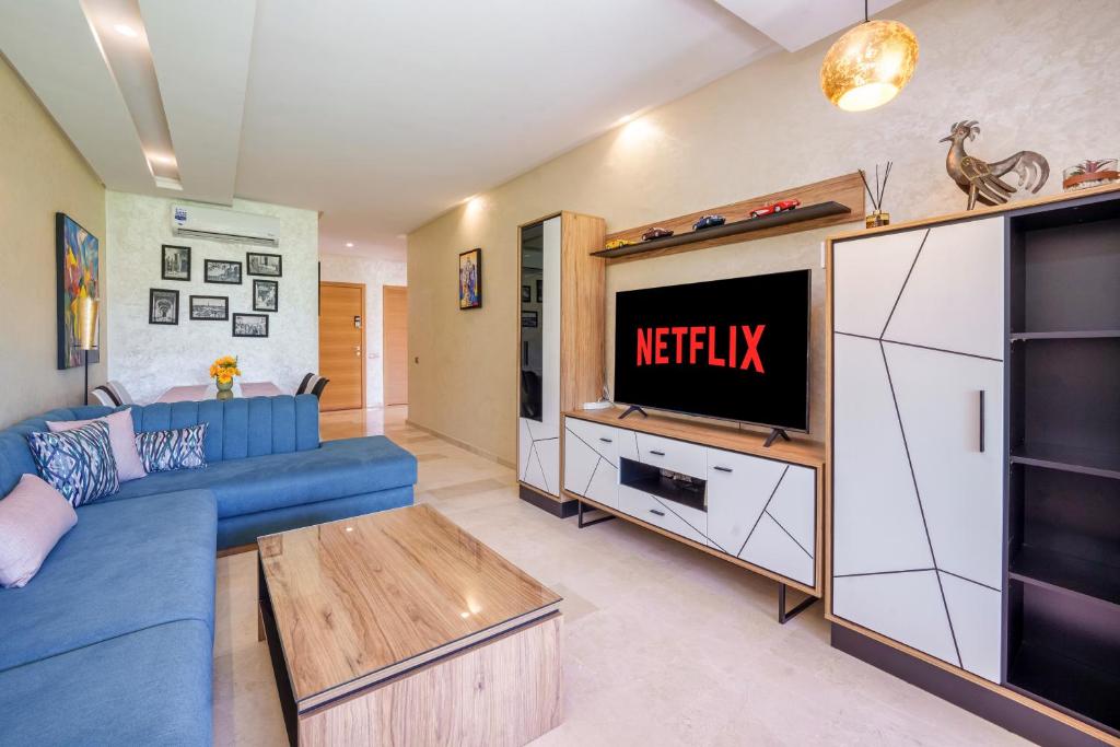a living room with a blue couch and a tv at Apart Confort Front Pool-Garden in Marrakesh
