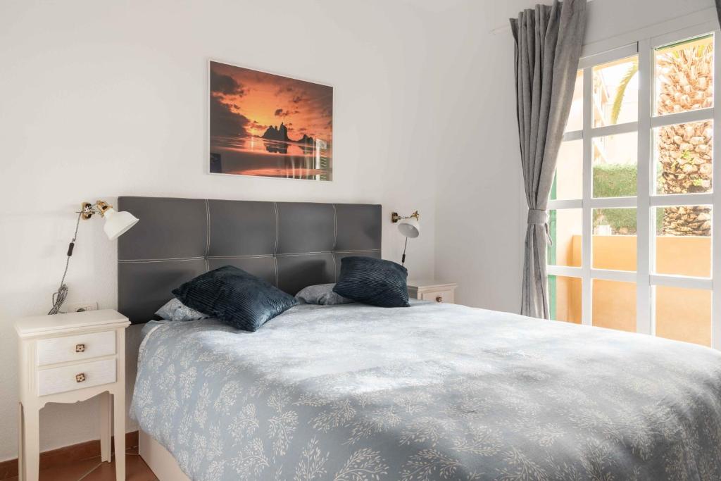 um quarto com uma cama grande e almofadas azuis em Acogedor vistas piscina y Teide em Santa Úrsula