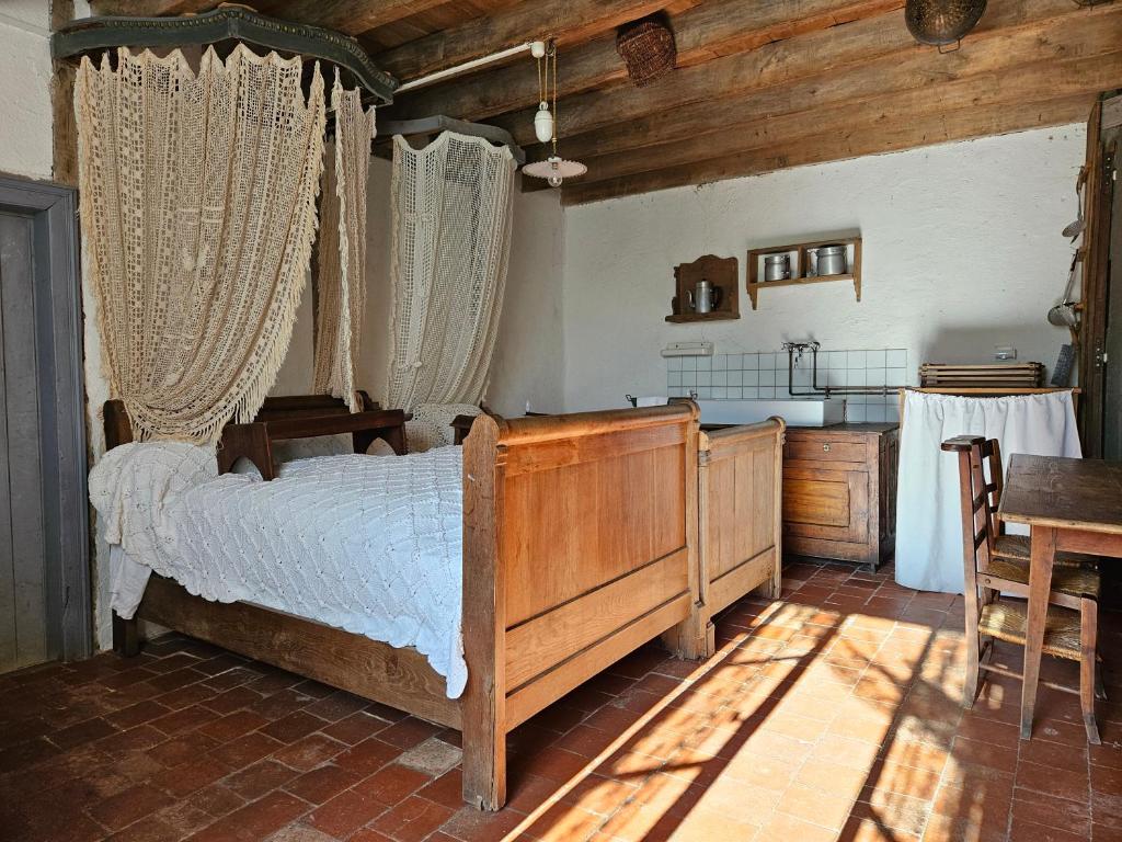 a bedroom with a bed and a table and a kitchen at Le Porteau Enchanteur in Sarzay