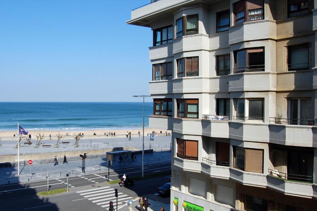 um edifício ao lado de uma praia com pessoas nele em Playa Gros - IB. Apartments em San Sebastián