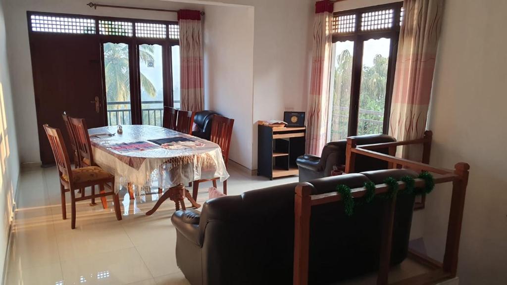 a living room with a table and chairs and windows at Dreamscape home stay in Kandy