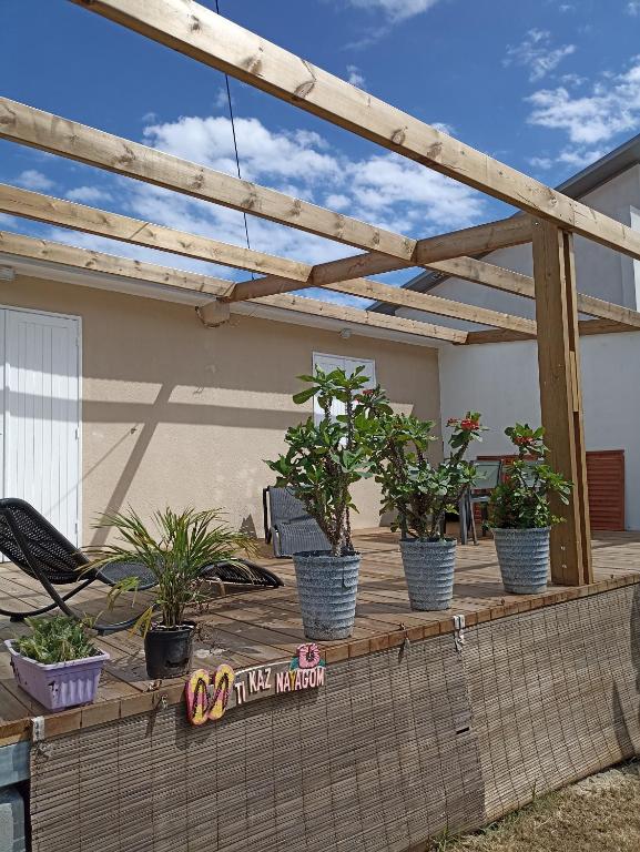 a wooden pergola with potted plants on a deck at Ti Kaz Nayagom in Saint-Pierre