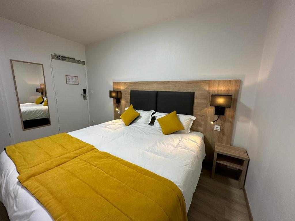 a bedroom with a large bed with a yellow blanket at Hôtel NOROTEL in Brumath